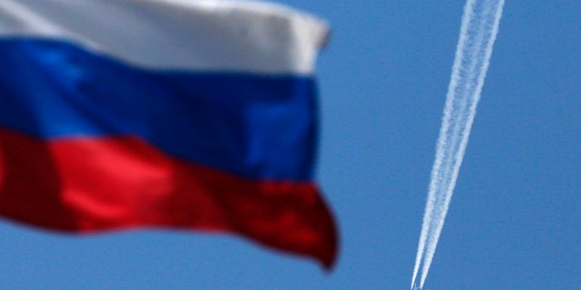 File photo - A wake left by a passenger plane is seen behind a Russian state flag as it passes over the Siberian city of Krasnoyarsk, August 7, 2014. (REUTERS / Ilya Naymushin)