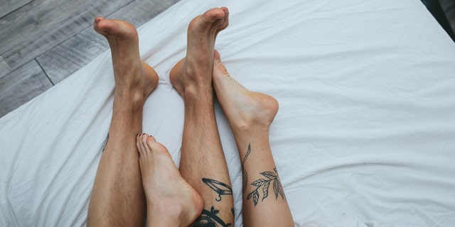 Young adult heterosexual couple lying on bed in bedroom, together with a dog