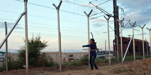 A girl plays next to the fence on the Macedonian border in Idomeni, Greece, Thursday, May 19, 2016. Thousands of stranded refugees and migrants have camped in Idomeni for months after the border was closed. (AP Photo/Darko Bandic)