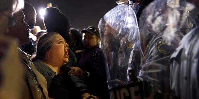 A protester yells at police outside the Ferguson Police Department, Wednesday, March 11, 2015, in Ferguson, Mo. Earlier in the day, the resignation of Ferguson police chief Thomas Jackson was announced in the wake of a scathing Justice Department report prompted by the fatal shooting of an unarmed black 18-year-old by a white police officer. (AP Photo/Jeff Roberson)
