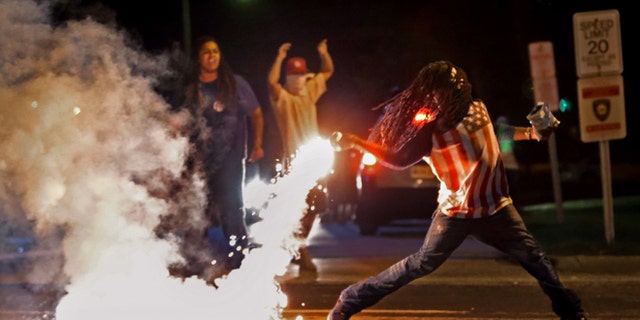 This iconic photo showed Edward Crawford returning a tear gas canister fired by police trying to disperse protesters in Ferguson, Missouri, April 20, 2015. (Robert Cohen/St. Louis Post-Dispatch via AP)