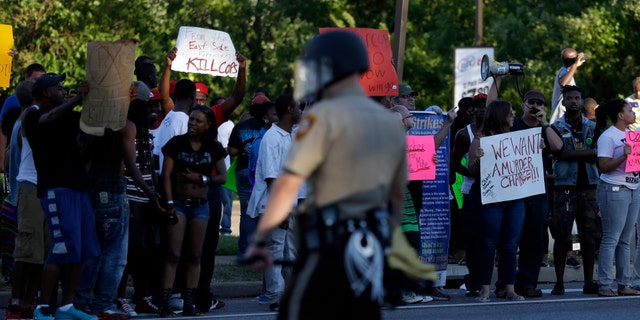 Aug. 12, 2014: Protesters line the street as police stand watch in Ferguson, Mo.
