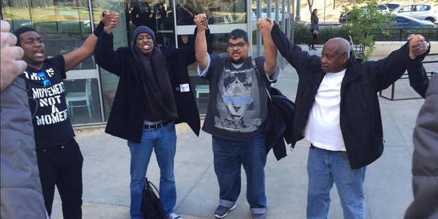 FILE- In this Feb. 2, 2016 file photo, activists hold hands and pray outside outside Los Angeles Police Department headquarters following the police commission's decision finding that the shooting of Charly "Africa" Keunang was justified in Los Angeles. Three Los Angeles police officers who fatally shot Keunang, a black homeless man on Skid Row last year, will not face criminal charges according to a report released Thursday, Dec. 1, by the district attorney. (AP Photo/Amanda Lee Myers, File)