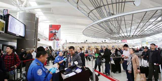 FILE - In this Oct. 30, 2014, file photo, a TSA officer, left, checks a passenger's ticket, boarding pass and passport as part of security screening at John F. Kennedy International Airport in New York. A court challenge over the difficulty for airline passengers to remove their names from the U.S. government’s no-fly list is taking an unexpected twist, now focusing on the mysterious ways federal agents add passenger names to the list in the first place. (AP Photo/Mark Lennihan, File)