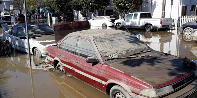 Cars are partially submerged and covered in mud from receding floodwaters Thursday, Feb. 23, 2017, in San Jose, Calif. Thousands of people evacuated from a flood in San Jose, California, returned home Thursday amid warnings to be careful about hygiene and handling food that may have come into contact with flood water. (AP Photo/Marcio Jose Sanchez)