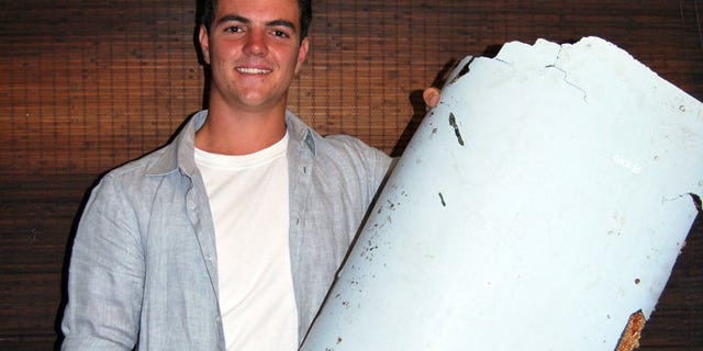 Liam Lotter poses with a piece of debris thought to be part of the missing Malaysia Airlines Flight MH370, in Wartburg, South Africa.