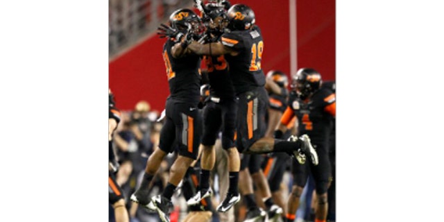 Oklahoma State cornerback Brodrick Brown (19), Colton Chelf, center, and Shaun Lewis, right, celebrate a missed field goal attempt by Stanford during overtime of the Fiesta Bowl NCAA college football game Monday, Jan. 2, 2012, in Glendale, Ariz.