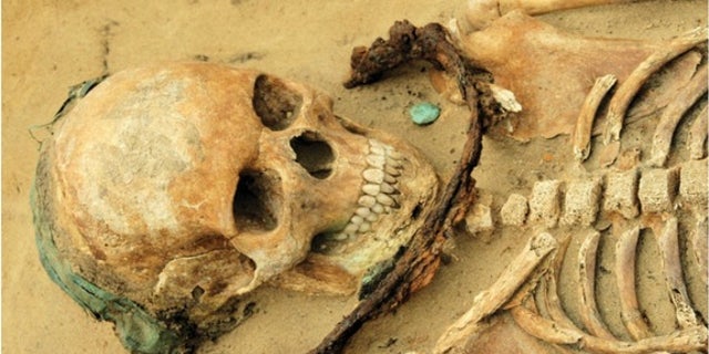In addition to the sickle placed at her neck, the teenage girl seems to have been buried with a copper headband and a copper coin.