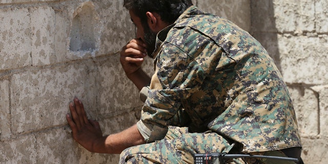 A U.S.-backed Syrian Democratic Forces fighter looks through a hole on the front line of the industrial district on the eastern side of Raqqa.