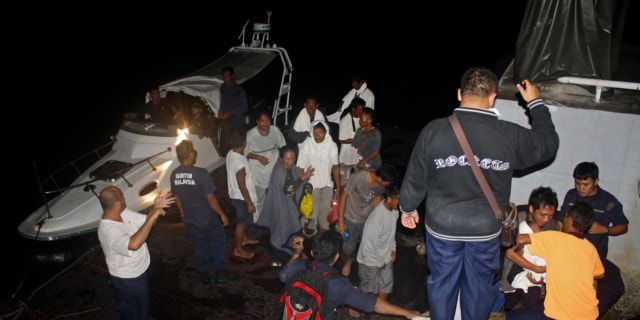 FILE: July 18, 2013: This photo released by Malaysian Maritime Enforcement Agency shows Indonesian passengers who were rescued from an overturned boat at a jetty in Tanjung Sedili, Johor state, Malaysia.