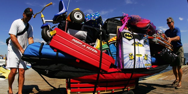 FIRE ISLAND, NY - SEPTEMBER 5: Mirk Davis (in front) gets help from a friend as he pulls his wagon full of vacation supplies on September 5, 2005 at Ocean Beach on Fire Island off the coast of Long Island in New York. Ferry service to Fire Island began in 1856; passengers could take the Long Island Railroad from Brooklyn to Thompson (now Brentwood), get a stage to Islip, and get on the waiting ferry. Nearly 150 years later, transportation to Fire Island is basically the same. Although there are more ferries from different locations, you do have to take a ferry to get to most parts of Fire Island. Fire Island, which is the only developed barrier island in the United States without roads, is located 45 minutes outside of New York City, just a 30 minute ferry ride across the Great South Bay. Fire Island is a premier getaway spot for families and friends. Sand dune beaches rollout into the Atlantic Ocean on the south side of the island, while the north side has dining and bars overlooking the bay. (Photo by Ezra Shaw/Getty Images)