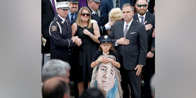 Isabella Tolley, 8, holding a blanket with a picture of her father.