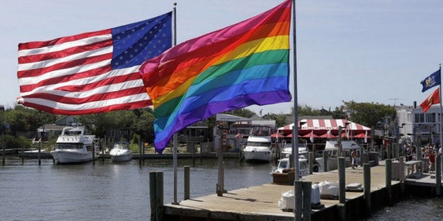 An American flag and a gay pride banner wave together on Fire Island, a barrier island off New York that is a popular summer destination for LGBT revelers. (AP)