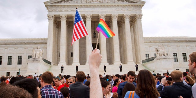 A man holds a U.S. and a rainbow flag outside the Supreme Court in Washington after the court legalized gay marriage nationwide. 