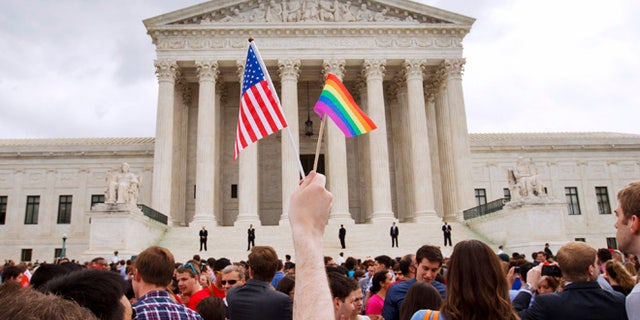 June 26, 2015: A man holds a U.S. and a rainbow flag outside the Supreme Court in Washington after the court legalized gay marriage nationwide. (AP)
