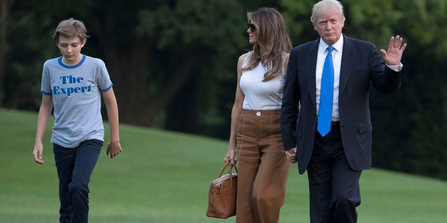 President Donald Trump waves as he walks with first lady Melania Trump and their son, Barron Trump, from Marine One across the South Lawn to the White House in Washington, Sunday, June 11, 2017, as they returned from Bedminster, N.J. (AP Photo/Carolyn Kaster)