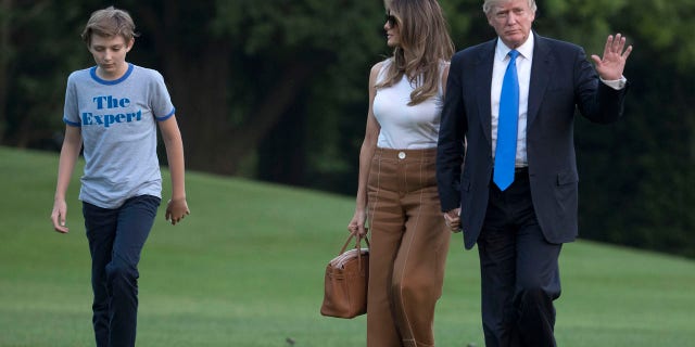 President Donald Trump waves as he walks with first lady Melania Trump and their son, Barron Trump, from Marine One across the South Lawn to the White House in Washington, Sunday, June 11, 2017, as they returned from Bedminster, N.J. (AP Photo/Carolyn Kaster)