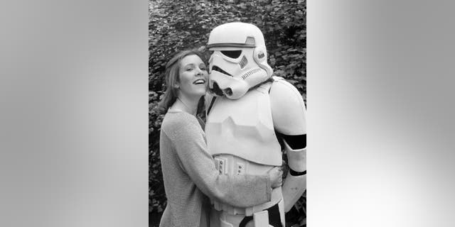 Actress Carrie Fisher hugs a person dressed as a stormtrooper in London in 1980.