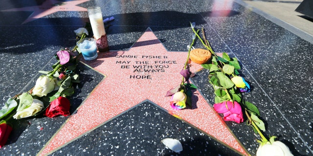 Flowers and candles dot an impromptu star on the Hollywood Walk of Fame for Carrie Fisher