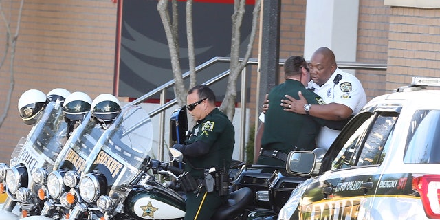 A Orange County Sheriff Motor deputy,center, gives support to a Orlando Police Motor officer,right, at Orlando Regional Medical Center after a OPD officer was shot and severely injured while responding over night to a domestic dispute call.