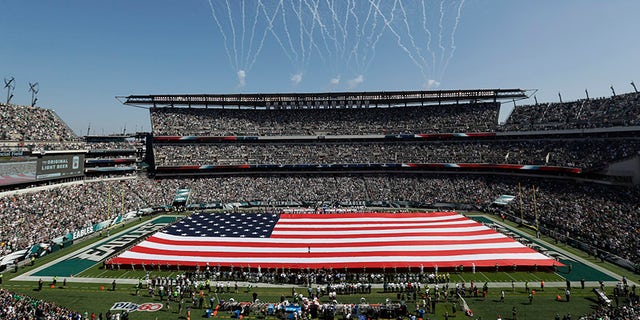 An American flag covers the field before an NFL game between the Philadelphia Eagles and the New York Giants in Philadelphia.