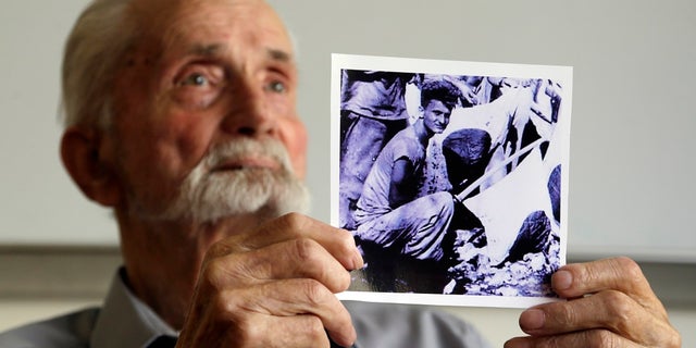 WWII veteran Marvin Strombo holds up a photo of himself taken during the battle on Saipan.