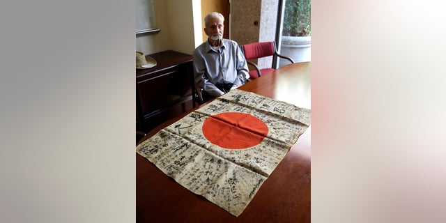 WWII veteran Marvin Strombo sits with the flag he will return to a fallen Japanese soldier's family.