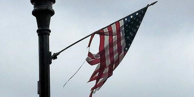 Most of the two dozen flags hanging from the black light posts that line Main Street in Derby, Conn. are either tattered and torn, have broken sticks that have been pieced together with duct tape or are laying on the ground. (New Haven Register)