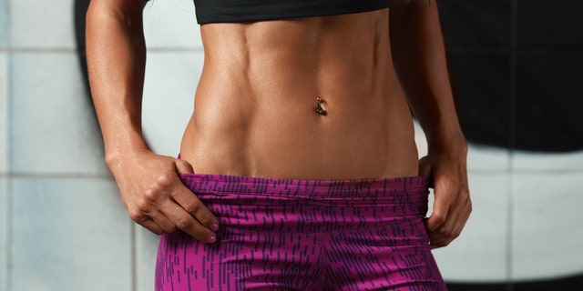 Fitness sexy woman showing abs and flat belly. Beautiful muscular girl, shaped abdominal, slim waist