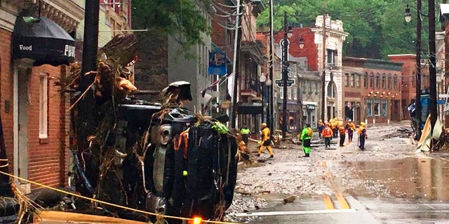 Rescue personnel walk along Main Street in Ellicott City, Md.