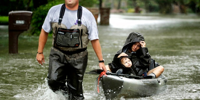 People evacuate a neighborhood in west Houston inundated by floodwaters from Tropical Storm Harvey on Monday, Aug. 28, 2017, in Houston, Texas. (AP Photo/Charlie Riedel)