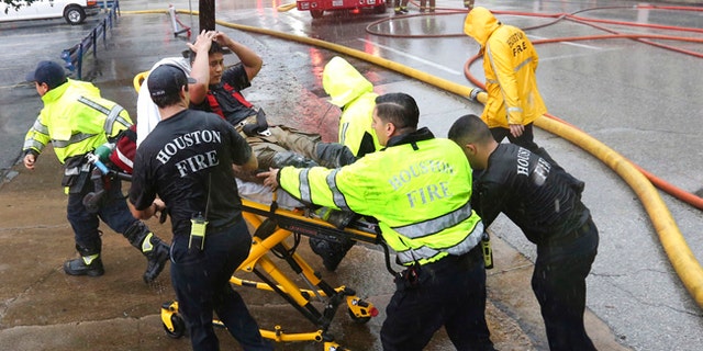 Rain from Tropical Storm Harvey falls as a firefighter is wheeled to a waiting ambulance after he became fatigued while fighting an office building fire in downtown in Houston, Texas, Monday, Aug. 28, 2017. (AP Photo/LM Otero)