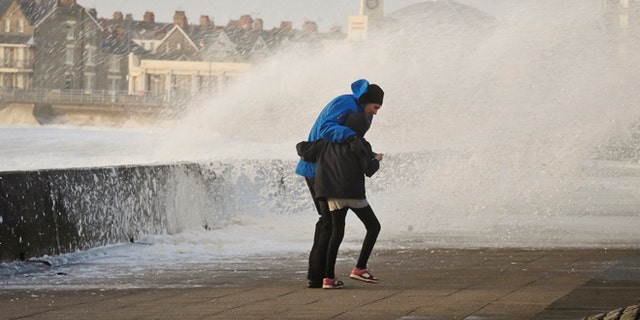 People struggle to make their way along the Esplanade, Porthcawl, south Wales, as the region continues to be battered by high winds and heavy rain.