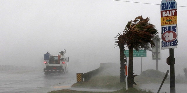 A work truck drives on Hwy 24 as the wind from Tropical Storm Florence blows palm trees in Swansboro North Carolina on Thursday.