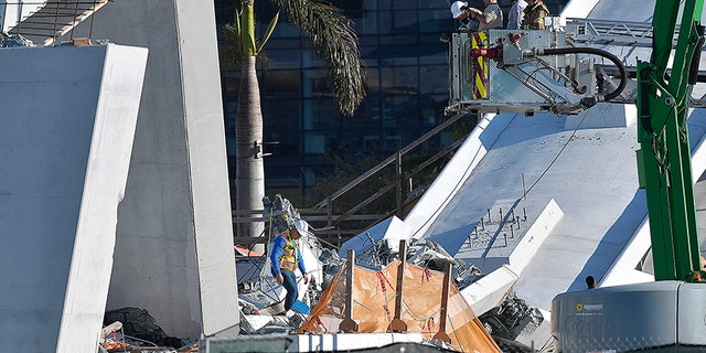 Miami-Dade Fire Rescue personnel inspect the scene following Thursday's bridge collapse.