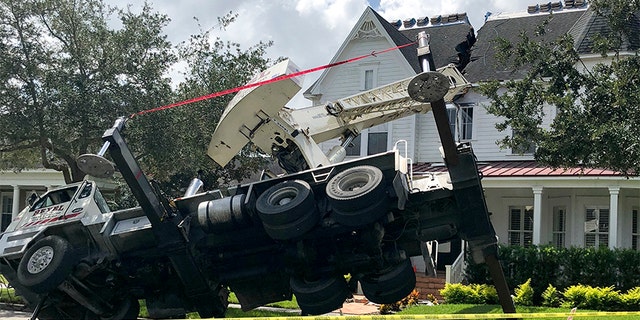 This photo released by the Orlando Fire Department shows a truck carrying a crane tipped over, damaging a house in Orlando, Fla., on Tuesday.