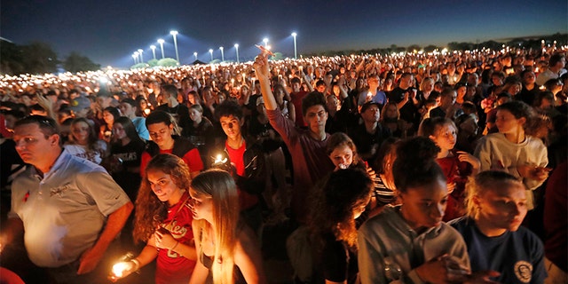 People hoist up their candles during a vigil for the victims of the Wednesday shooting at Marjory Stoneman Douglas High School.