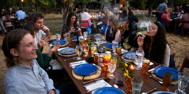 In this Oct. 2, 2016 photo, diners smoke marijuana as they eat dishes prepared by chefs during an evening of pairings of fine food and craft marijuana strains served to invited guests dining at Planet Bluegrass, an outdoor venue in Lyons, Colo.