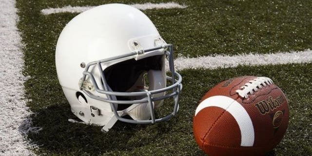 Football and football helmet on gridiron