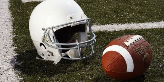 Football and football helmet on gridiron