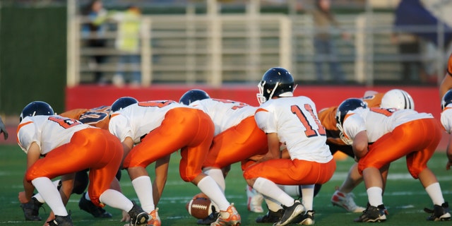 High school football players in their play stance at the line of scrimmage during a football game