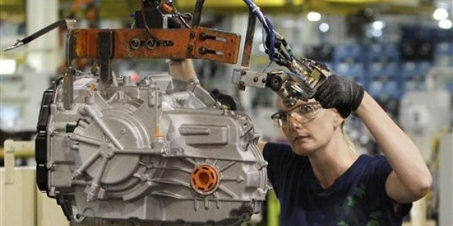 In this June 9 file photo, a line worker moves a transmission from the assembly line to a pallet at the Ford Van Dyke Transmission Plant in Sterling Heights, Mich.