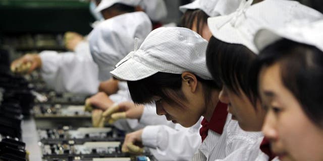 Workers at Foxconn are provided with masks at the start of each shift. In this Wednesday, May 26, 2010, file photography, staff members work on the production line at the Foxconn complex in Shenzhen, China.