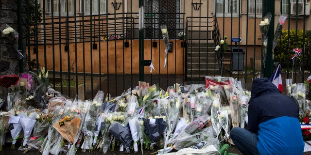 A man places flowers at the main gate of the police headquarters in Carcassonne on Saturday, March 24, 2018, following an attack on a supermarket in the south of France on Friday.