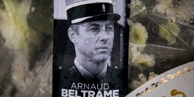 A photo of Lieutenant Colonel Arnaud Beltrame placed on a bunch of flowers at the main gate of the Police headquarters in Carcassonne, France, Saturday, March 24, 2018, following an attack on a supermarket in Trebes in the south of the country on Friday.
