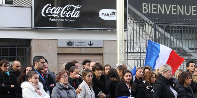 People stand for a minute of silence near the Stade de France stadium in Saint Denis, outside Paris.