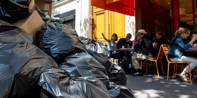 People have lunch next to overflowing trash bags in Paris on Thursday.