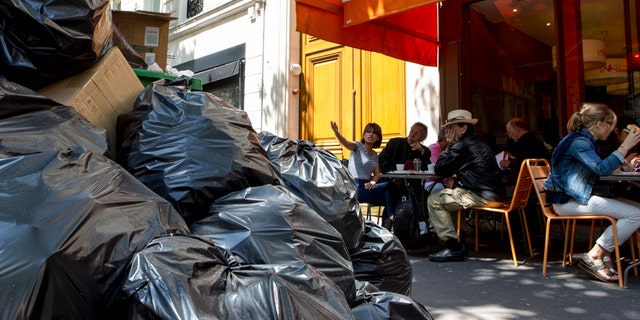 People have lunch next to overflowing trash bags in Paris on Thursday.