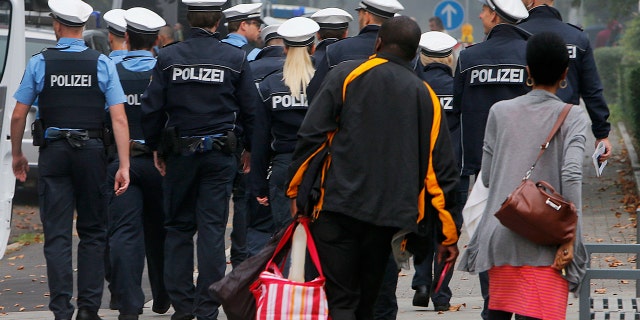 A couple has left its apartment and walk behind police during an evacuation of more than 60 000 people in Frankfurt, Germany, Sunday, Sept. 3, 2017.