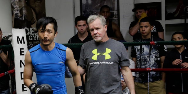 Zou Shiming, left, a two-time Olympic gold medalist and three-time World Amateur Champion from China, exits the ring with trainer Freddie Roach after a workout, Wednesday, June 8, 2016, at Mendez Gym in New York. Zou will be defending his WBO International flyweight title and No. 2 world rating in a 10-round bout against Jozsef Ajtai of Hungary,Saturday, June 11 at Madison Square Garden. (AP Photo/Mark Lennihan)